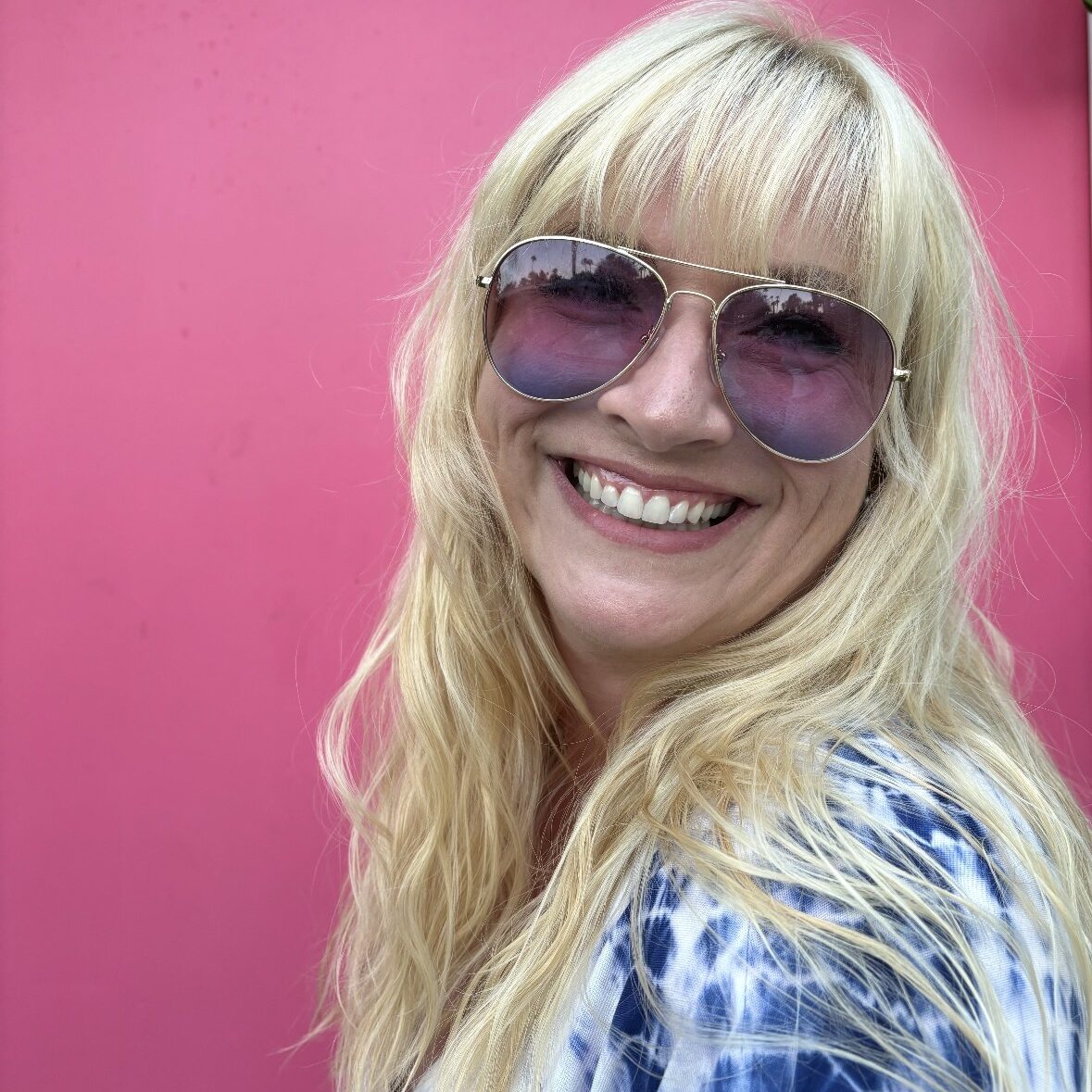 Carin O'Hara smiling in front of a pink background.