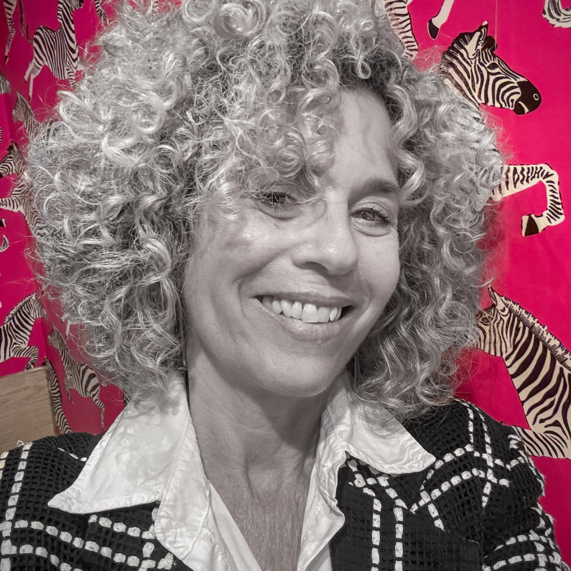 Headshot of Claudia Berman in black and white with a colorful background.